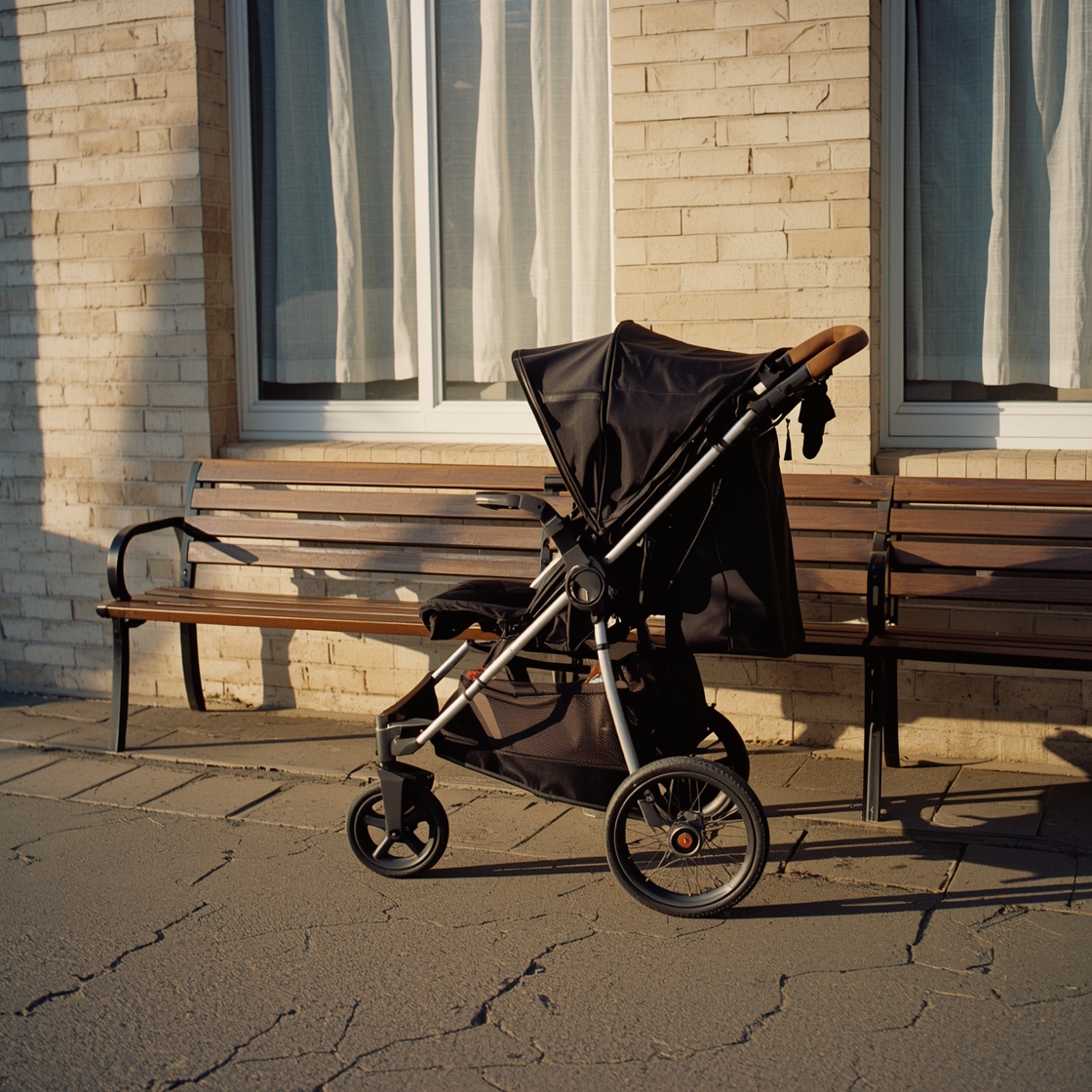 A medium dog stroller parked on a sidewalk beside a bench